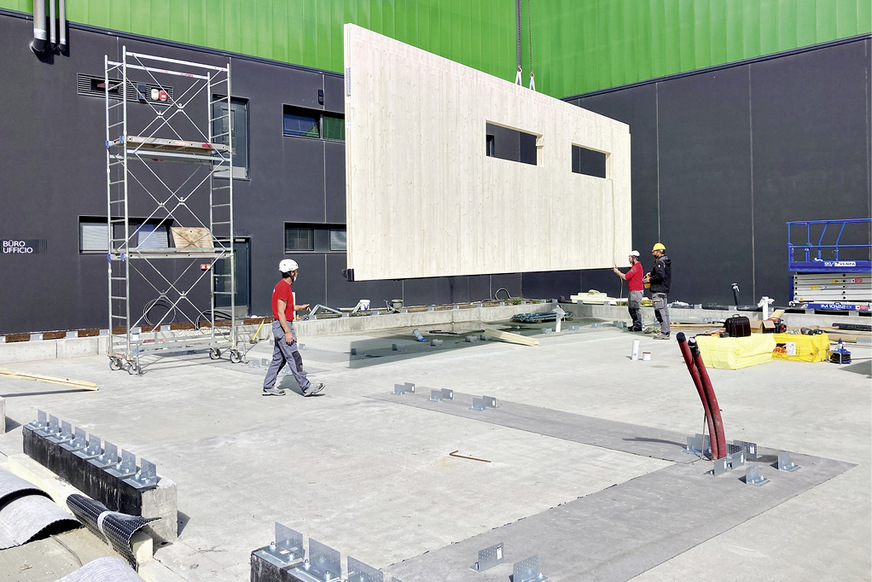 Die vorelementierten Wände schweben mit dem Kran auf die Baustelle.