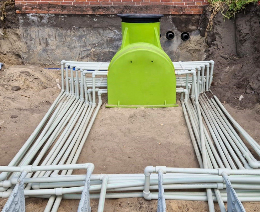 Die Vor- und Rücklaufrohre der Erdkollektoren werden vor Ort kunststoffverschweißt. Über einen Verteilerschacht ist die Kontrolle der Stränge möglich. Rechts vom Verteiler ist die Kernbohrung für den Anschluss an die Wärmepumpe zu sehen.