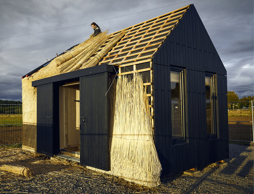 2 Dieses Experimentalhaus aus schnell nachwachsenden Rohstoffen haben die Studierende﻿n der Universität Bonn in Klein Altendorf im Rahmen eines Forschungsprojektes selbst gebaut. Hier deckt der Projektbetreuer Jano Knopp höchstselbst das Dach mit Miscanthus ein.