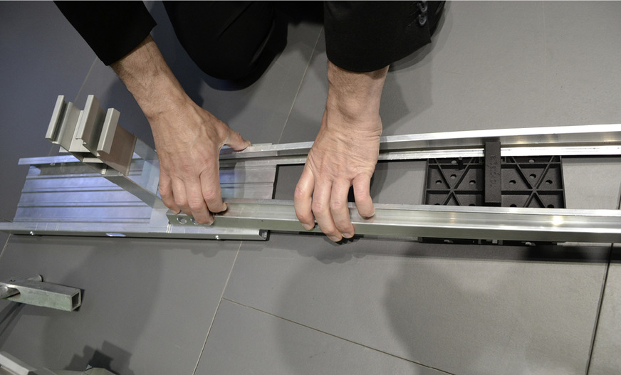 Zunächst drückt der Handwerker das Ende der Verbinderschiene zusammen und schiebt sie in das Grundschienenstück.