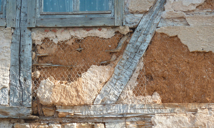 Teilstück einer historischen Fachwerkwand: Im Bereich der mit Draht gesicherten Schadstelle unter dem Fenster ist noch deutlich das Flechtwerk samt Lehmschlag zu erkennen.