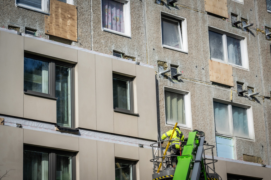 Bauarbeiter montiert eines von 228 vorgefertigte Fassadenelementen in der Albert-Schweitzer-Straße 2-14 in Ludwigsfelde. Mit dem Sanierungskonzept lassen sich mit weniger Fachkräften mehr Gebäude in kürzerer Zeit energetisch modernisieren.