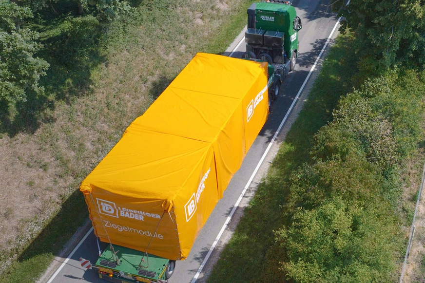 Lkws transportieren die Ziegelmodule zur Baustelle.