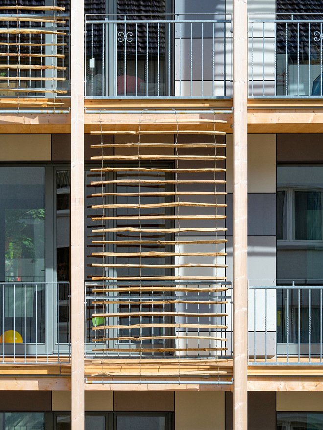 4-1 Die gebäudebreiten Balkone mit ihren senkrechten Holzstelen prägen die Straßenfassade.