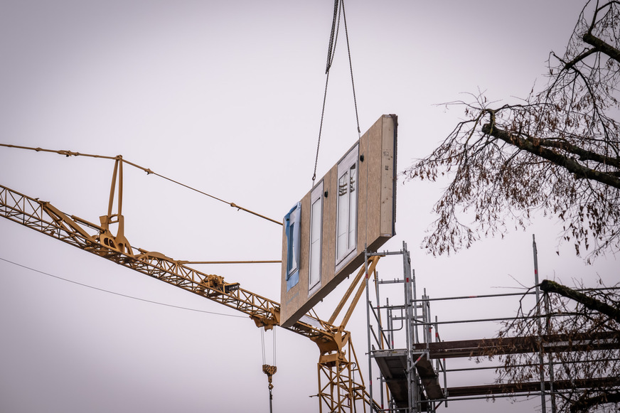 Vorgefertigte Holzrahmenelemente werden auf der Baustelle montiert und ermöglichen eine schnelle, energieeffiziente Sanierung der Bestandsgebäude.