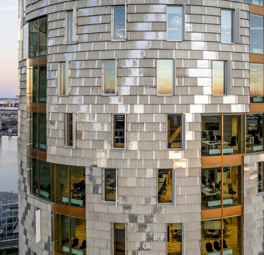 Die geschuppt angeordneten, hinterlüfteten Aluminium-Trapezbleche verleihen der Fassade eine „Chabby-Struktur“ und dokumentieren das Re-Use-Konzept.