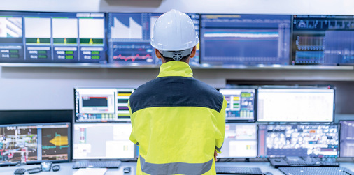 Ingenieur im Kontrollraum beim Monitoring über zahlreiche Bildschirme