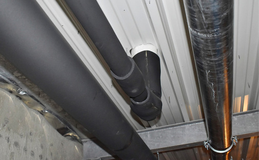 Entwässerungsrohre unter einer Hallendecke: Eine Dämmung verhindert Kondensation und damit Feuchteschäden (rechts: noch ungedämmte Notentwässerung).