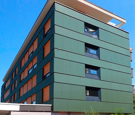 8 Fassadenanlage aus rahmenlosen PV-Modulen mit grün geriffelter Ober­fläche an einem Mehrfamilienhaus in Basel