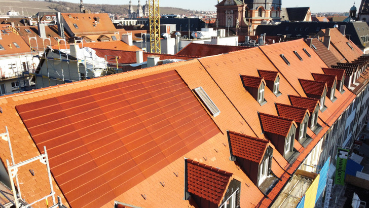 Die roten solaren Dachelemente fügen sich fast perfekt in die Dachhaut des historischen Gebäudes in Würzburg ein. Unweit des Doms war aus denkmalschützerischen Gründen keine andere Lösung möglich.