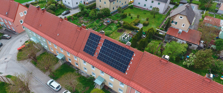 Das Happening-System, eine Kaskade aus Wärmepumpen, kommt in einem zusammenhängenden Riegel aus fünf Gebäuden in Liezen zum Einsatz. Heizzentrale und PV sind im beziehungsweise auf dem mittleren Gebäude installiert. Klein in weiß hinter dem Gebäude sind die Außeneinheiten der Luftwärmepumpen zu erkennen. Strombilanz und Anteil erneuerbarer Energien im Happening-Sys﻿tem. Beim Happening-­System liegen die Investitionskosten deutlich über dem Referenzsystem. Nach etwa 13 Jahren haben sich diese amortisiert.