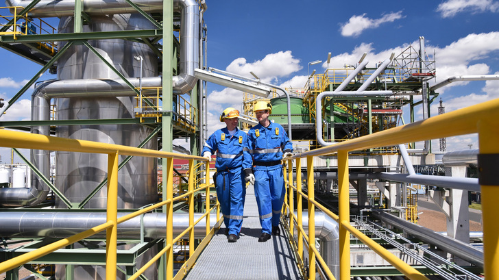 chemical industry plant - workers in work clothes in a refinery with pipes and machinery