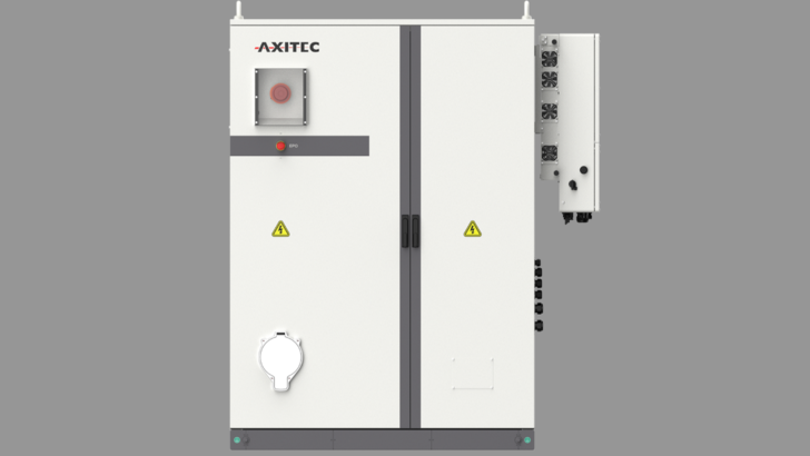 Großer weißer Schaltschrank mit AXITEC-Logo und Warnhinweisen auf grauem Hintergrund. - © Axitec