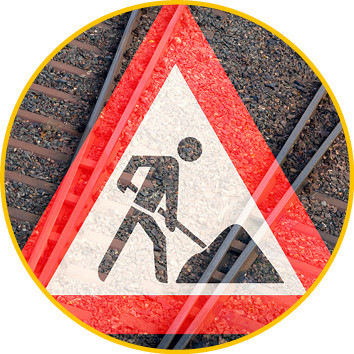 Warnschild mit einer grabenden Person, überlagert von Eisenbahnschienen, das auf Bauarbeiten hinweist. - © Bild: bluedesign - stock.adobe.com