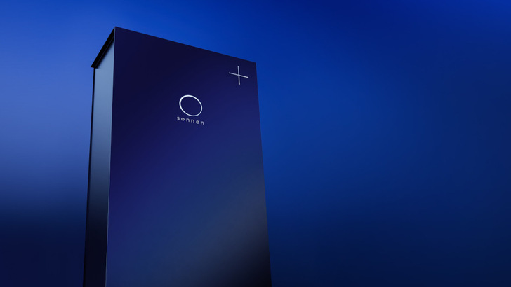 Eine hohe, schlanke, dunkelblaue Sonnen-Batterieeinheit steht vor einem blauen Hintergrund mit Farbverlauf. - © Sonnen