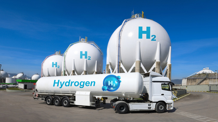 Ein Wasserstofftankwagen parkt vor großen weißen Wasserstofftanks auf einem Industriegelände. - © bulentcamci - stock.adobe.com
