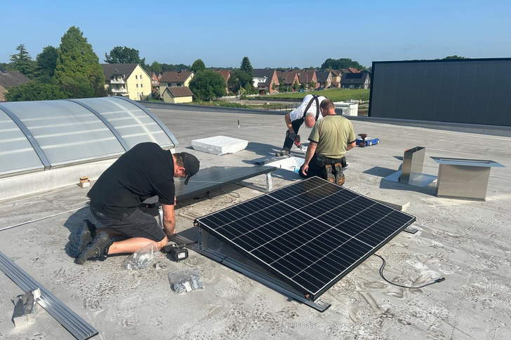 Fachkräfte montieren PVT-Kollektoren auf dem Dach des SHK-Betriebs Mussenbrock. Im System arbeiten sie mit einem Speicher, einer Wärmepumpe und Kühldecken zusammen.