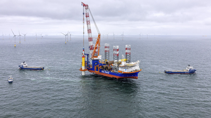 Bau des Offshore-Windparks Nordseecluster A von RWE und Norges Bank Investment Management. Anfang November 2025 meldete RWE, dass die Baufirmen alle 44 säulenförmigen Fundamente, Monopiles mit 85 Meter Länge und 1.500 Tonnen Gewicht, in den Boden getrieben haben (Foto – in Nachbarschaft zum Ørsted-Nuveen-Windpark Gode Wind). RWE setzt hier fortentwickelte Monopiles ein, die das als getrenntes Übergangselement aufmontierte Transition Piece zum Aneinanderfügen von Gründungspfahl und Windturbinenturm erübrigen. Diese Adapter sind im Design nun als spezialisierte Monopile-Verlängerung enthalten. Zugleich brachten die Monteure die sekundären Stahlelemente wie Leitern, Innenausstattung der Unterwassersäulen und Fundamentarbeitsplattform an. Auch beide Fundamente der zwei Umspannplattformen hat Baudienstleister Van Oord schon installiert. 2026 folgen die 15-Megawatt-Anlagen von Vestas.