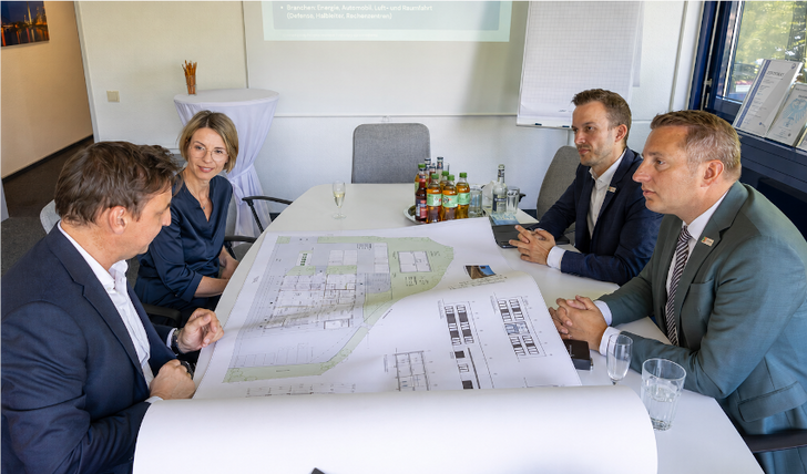 Pläne für die neue Fabrik für Sicherheitstechnik bei Neoxid Hydrogen. Am Tisch sitzen links Dr. Dieter Ostermann, Sandra Ostermann (beide Neoxid Hydrogen AG), und rechts Regierungspräsident Thomas und Nils Pöstgens (beide Bezirksregierung Düsseldorf).