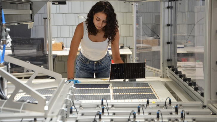 Die Projektleiterin am Fraunhofer ISE, Najwa Abdel Latif kontrolliert die verschalteten Solarzellen am Schindel-Matrix-Stringer des Fraunhofer ISE.