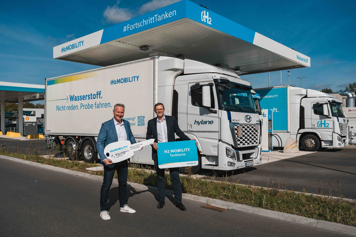 Peter Röskes, Schreck + Batz Logistik, und Martin Jüngel, H2 MOBILITY, vor dem Miet-Lkw an der neuen Wasserstofftankstelle auf dem Autohof Hannover Airport (v. l. n. r.).