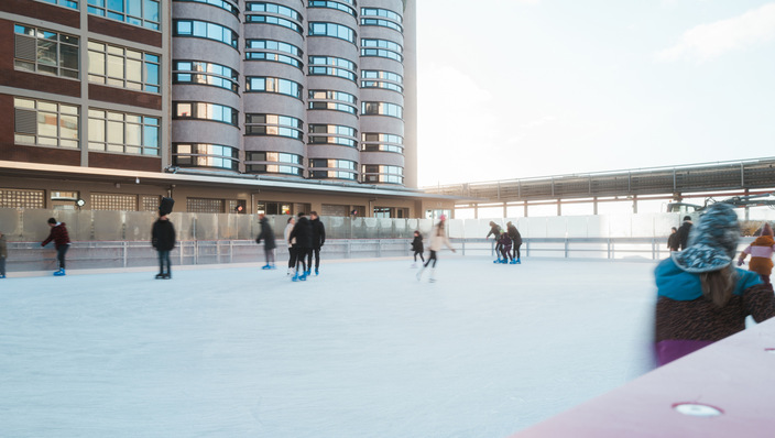 Eislaufbahn über dem Oberflächenkaltwasserspeicher des Bremer Überseeinsel-Quartiers vor dem zum Hotel umgebauten ehemaligen Kellogg-Speichersilo
