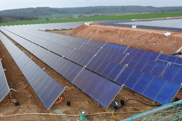 855 Flachkollektoren speisen in Bracht einen saisonalen Erdbeckenspeicher, rechts im Bild noch offen. Um die Auskühlung zu reduzieren, wird er mit einer schwimmenden Dämmung abgedeckt. Zum Schutz der Systemkomponenten des Nahwärmenetzes ist das Heizwasser im Speicher gereinigt worden.