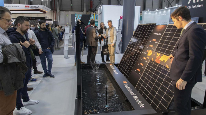Menschen beobachten einen Mann, der auf einer Technologieausstellung Solarzellen über einem Wasserdisplay vorführt. - © Genera