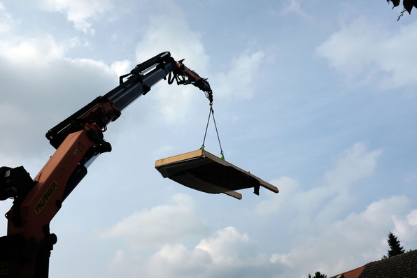 Vorgefertigtes Fassadenelement mit Strohdämmung hängt am Kran.